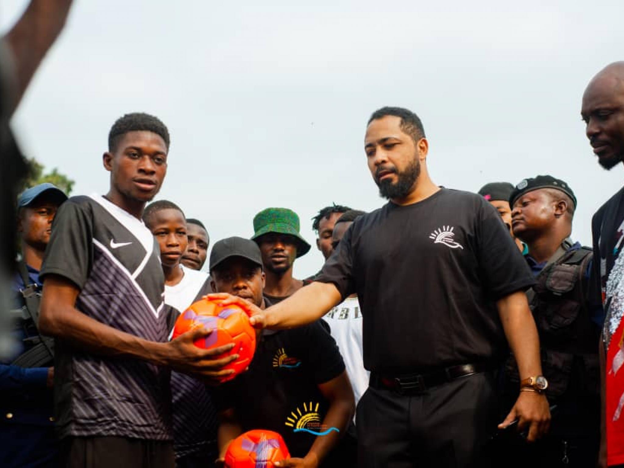 Mr Souleymane Kahuka (en polo noir avec logo de la Fondation Fleuve Congo) remet le ballon à l'une des équipes lors du lancement du tournoi du Fleuve
