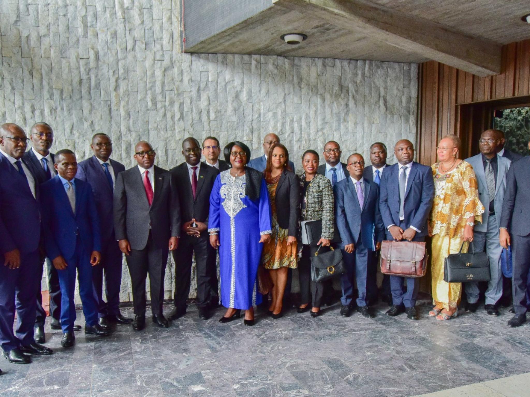 Photo de famille réunissant le Chef du Gouvernement, le ministre Julien Paluku, la délégation zambienne et les parties prenantes au projet de chaîne de valeur des batteries et véhicules électriques