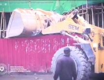 Un engin de l'hôtel de ville en pleine démolition de la palissade de la cité chinoise sur le Boulevard Sendwe