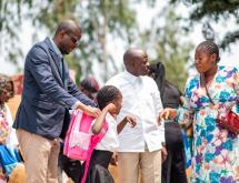 Le député national Éric Tshikuma, élu de la circonscription électorale de la FUNA, aide une écolière à enfiler son cartable lors de la cérémonie de distribution de kits scolaires.