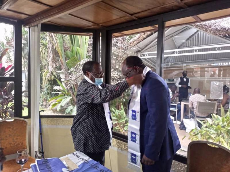 Le SG du parti ( À gauche) fait porter à Georges Mukuna, nouvelle autorité morale de l'URR le drapeau du parti