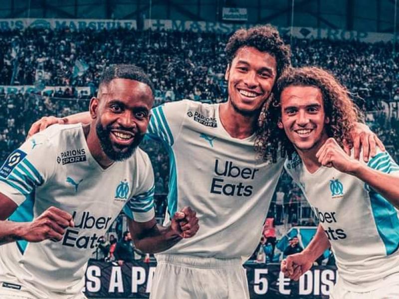 Cédric Bakambu en pleine célébration avec ses coéquipiers de l'OM, Kamara et Guendouzi.