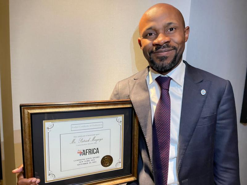 Tout souriant, le ministre Patrick Muyaya Katembwe tient en main,le prix lui décerné par le magazine américain "Forbes"