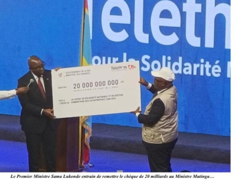 Le Premier ministre entrain de remettre un chèque de 20 milliards au ministre Modeste Mutinga