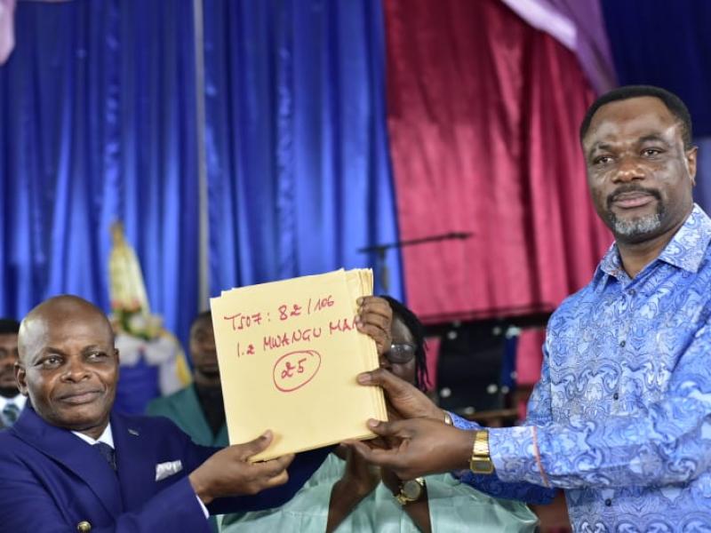 Le ministre de l'EPST, le professeur Tony Mwaba Kazadi remettant un exemplaire des diplômes d'État à l'inspecteur provincial principal de Mbujimayi