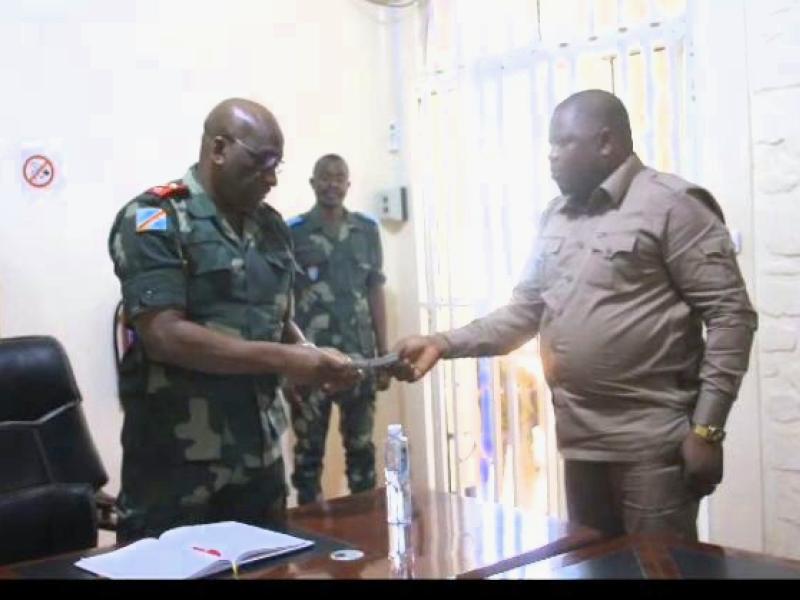 Le Lieutenant-Général Johnny Luboya N'kashama recevant des mains du député national Jean-Claude Trazza une enveloppe de 100.000 USD offerts par l'Assemblée Nationale pour soutenir les opérations militaires en Ituri.