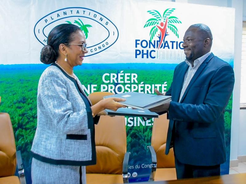  Mme Monique Gieskes, Directeur Général de PHC, et M. Junior Tchiteya, Directeur Exécutif de SAVE TOMORROW, procédant à l’échange des documents après la signature du protocole d'accord entre les deux organisations
