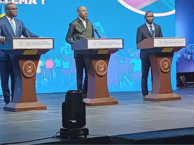 Le ministre de la Communication et Médias Patrick Muyaya, entouré du DGA de FONAREV, Kevin Ngunga Makiedi à sa gauche et du Professeur Serge Mayaka, membre de la coordination du comité scientifique préparation de la table ronde sur la GENOCOST