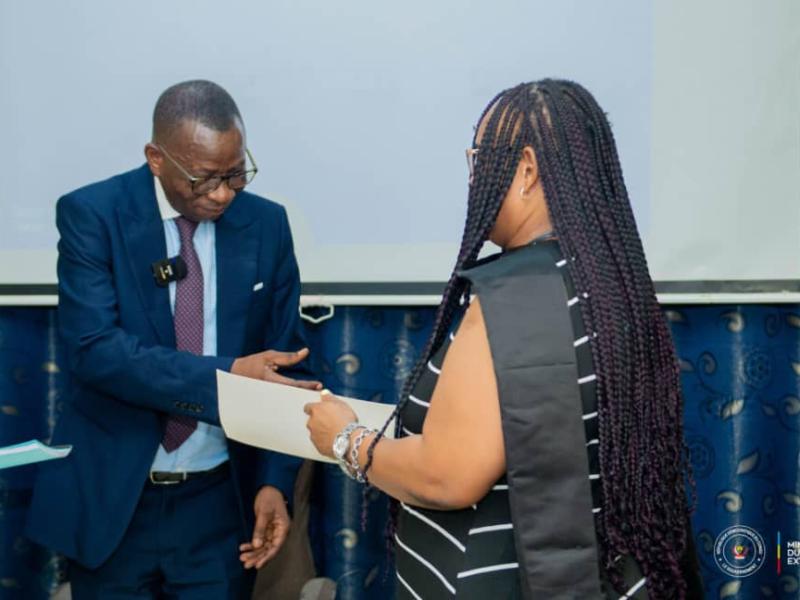 Jules Mwilu Mbo remet un brève à une femme congolaise formée par le ministère de Commerce extérieur pour promouvoir les exportations de la RDC à la ZLECAF