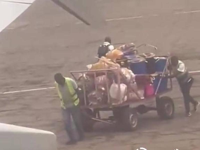 L'image des bagages transportés à l'aide de chariots poussés par les agents à l'aéroport de Bipemba