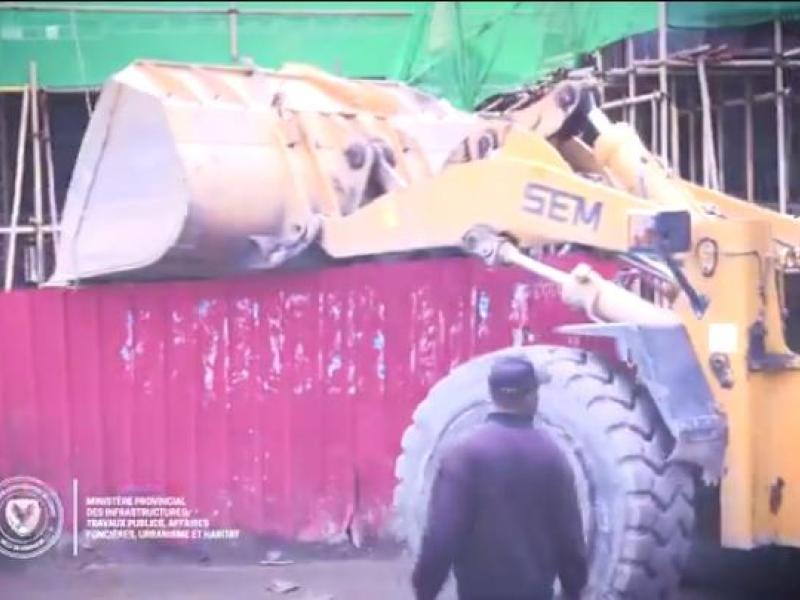 Un engin de l'hôtel de ville en pleine démolition de la palissade de la cité chinoise sur le Boulevard Sendwe