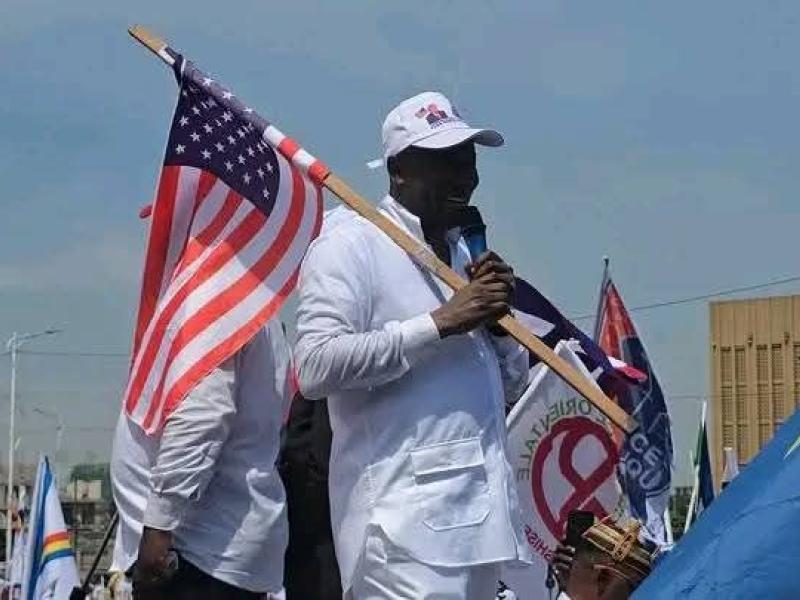 Augustin Kabuya, président ai l’UDPS, tenant un drapeau des USA pendant la marche de soutien des sanctions américaines contre Joseph Kabila