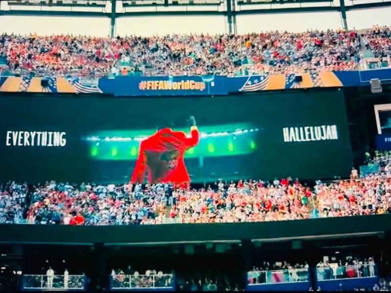L’image de Lumumba Vea, bras levé, en hommage à Patrice Lumumba, projetée sur les écrans géants du stade lors d’une prestation à la mi-temps de la finale de la Coupe du monde 2026
