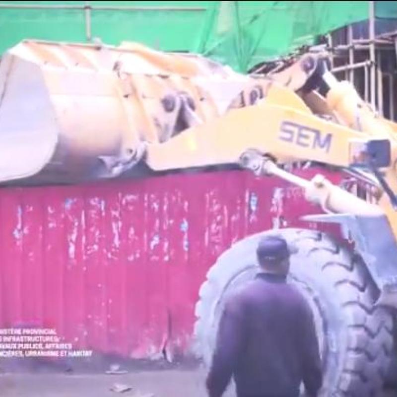 Un engin de l'hôtel de ville en pleine démolition de la palissade de la cité chinoise sur le Boulevard Sendwe