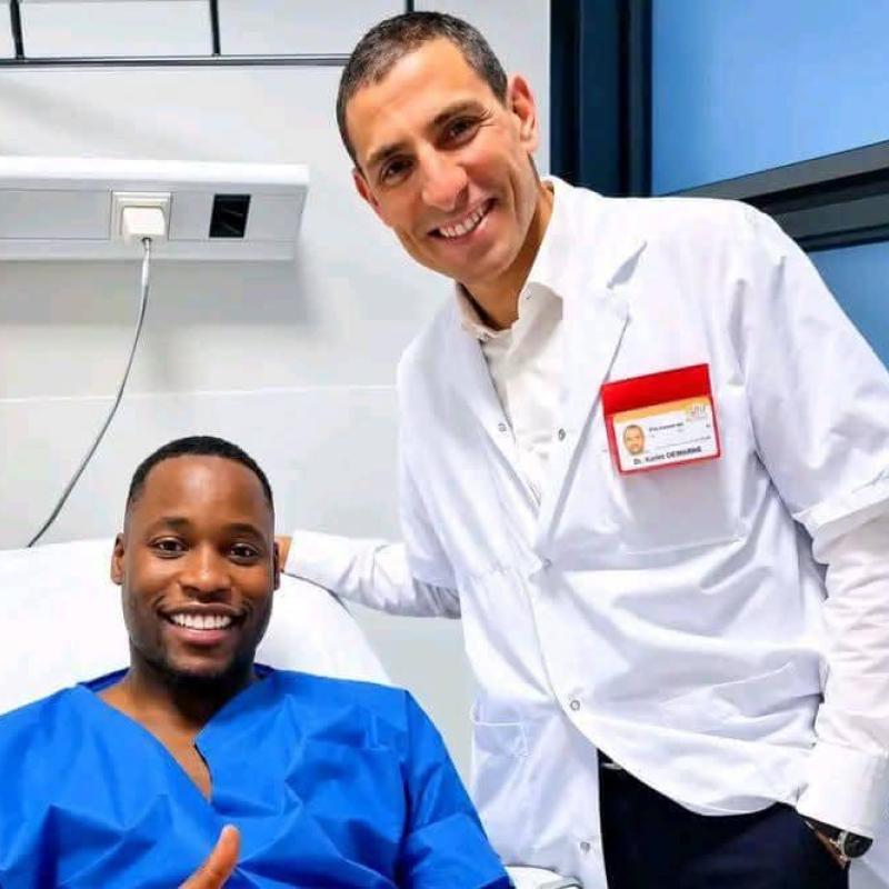 Lionel Mpasi sur un lit d'hôpital après les examens sur sa blessure