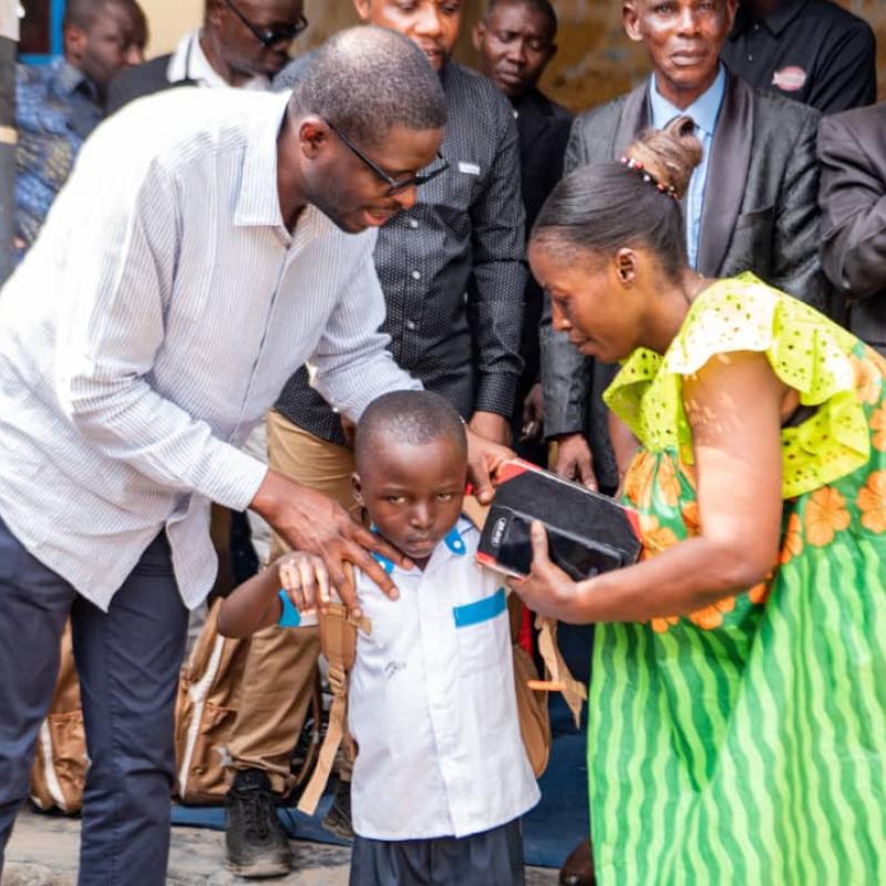 Le député national Éric Tshikuma remet à un élève l’une des 48 bourses « Patrick Muyaya », comprenant un kit scolaire ainsi que la prise en charge des frais de scolarité pour l’année scolaire 2026-2027.