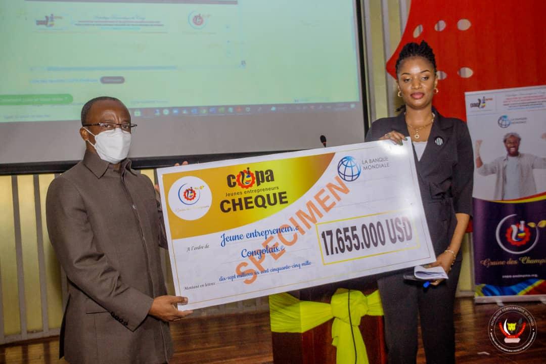 L'une des lauréats du concours Copa reçoit du ministre d'État Eustache Muhanzi son chèque