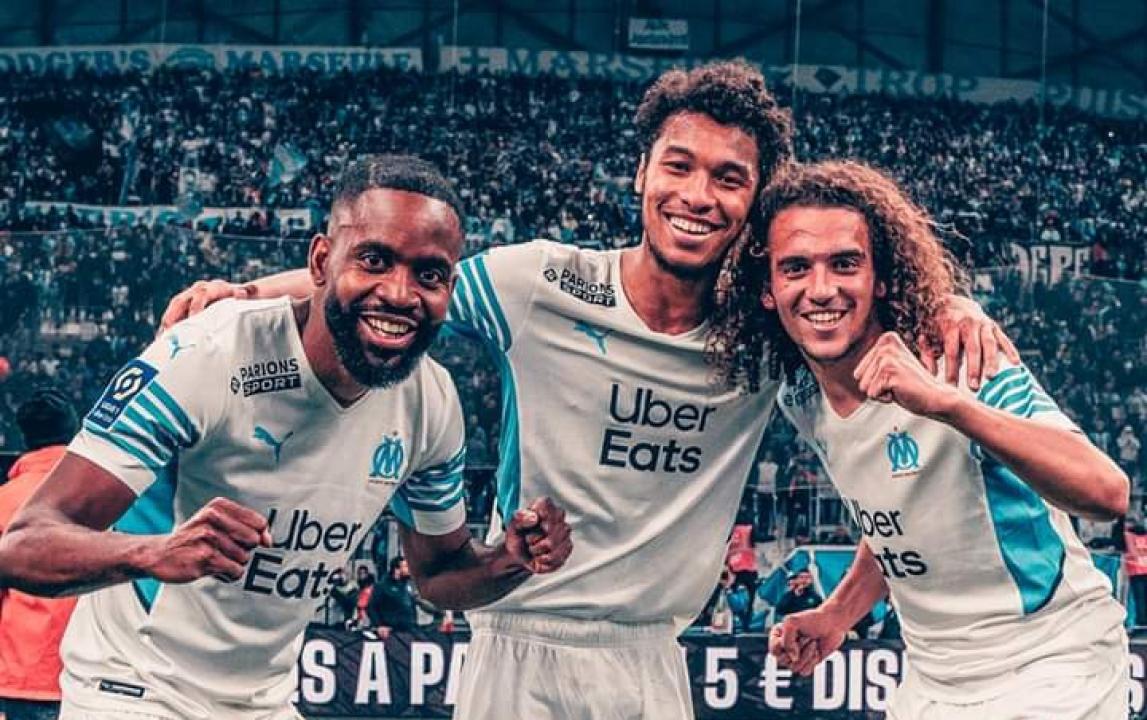 Cédric Bakambu en pleine célébration avec ses coéquipiers de l'OM, Kamara et Guendouzi.