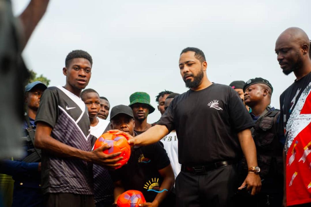 Mr Souleymane Kahuka (en polo noir avec logo de la Fondation Fleuve Congo) remet le ballon à l'une des équipes lors du lancement du tournoi du Fleuve