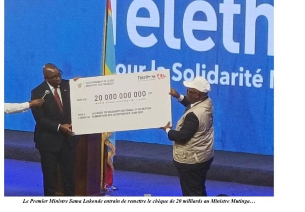 Le Premier ministre entrain de remettre un chèque de 20 milliards au ministre Modeste Mutinga