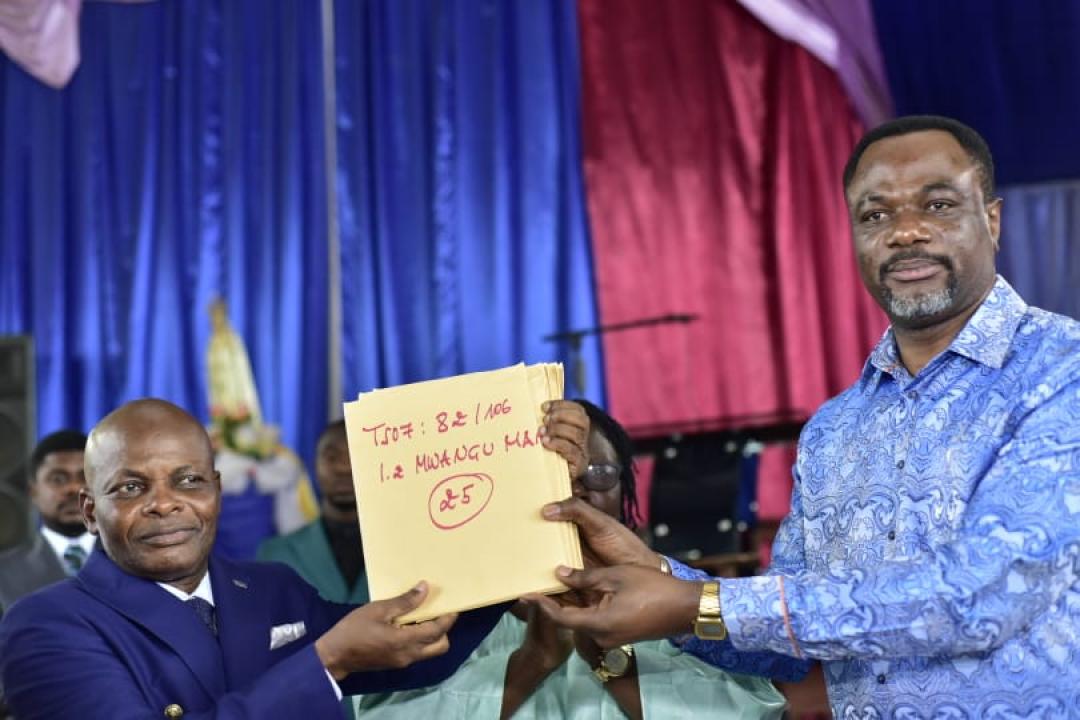 Le ministre de l'EPST, le professeur Tony Mwaba Kazadi remettant un exemplaire des diplômes d'État à l'inspecteur provincial principal de Mbujimayi