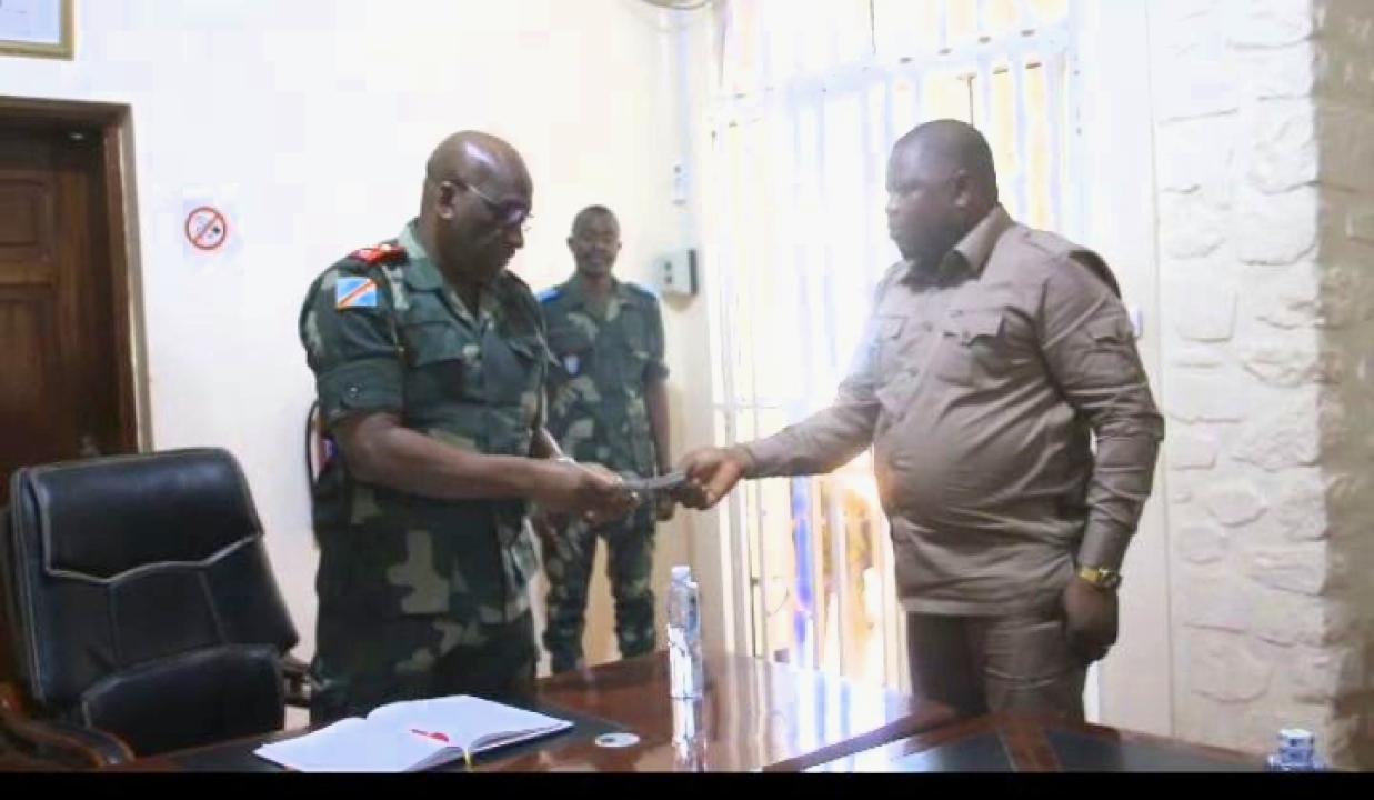 Le Lieutenant-Général Johnny Luboya N'kashama recevant des mains du député national Jean-Claude Trazza une enveloppe de 100.000 USD offerts par l'Assemblée Nationale pour soutenir les opérations militaires en Ituri.