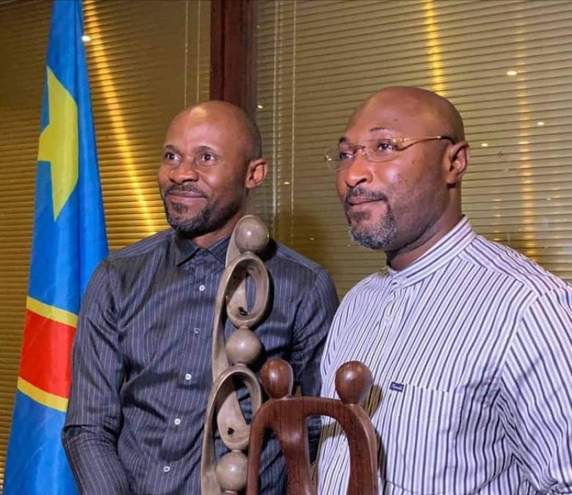 Le ministre de la communication et médias, Patrick Muyaya et Jésus Noël Sheke, PDG de l'Agence E-PROXY, recevant les trophées de la corporation des journalistes après leur réussite dans l'organisation de la communication du séjour du Pape François à Kinshasa.