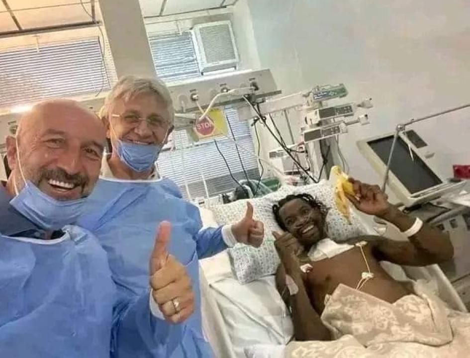 Jonathan Bolingi sur son lit d'hôpital, aux côté de son médecin et son manager.