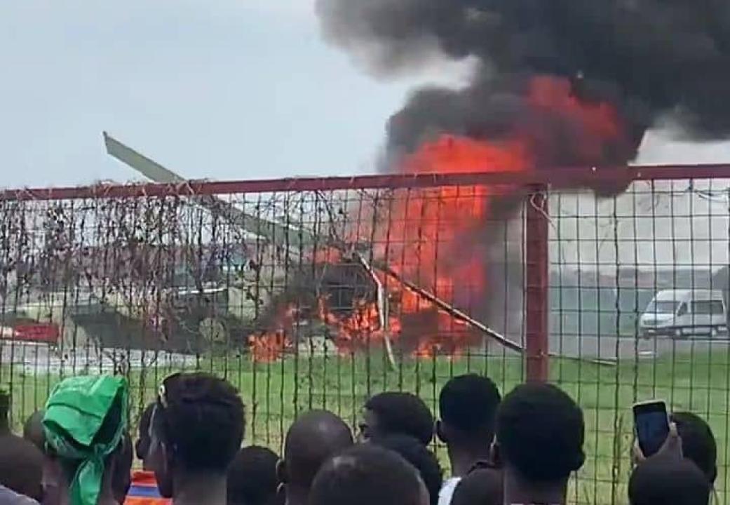 Les commerçants et les passants observent de près l’hélicoptère militaire en feu à l’aéroport de Ndolo
