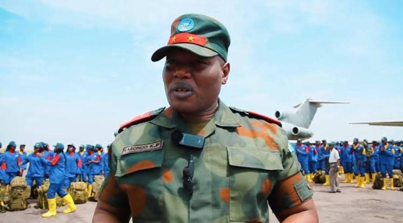 Le Lieutenant-Général Jean-Pierre KASONGO KABWUIK et en arrière-plan, les bâtisseurs du Service national à Kinshasa.