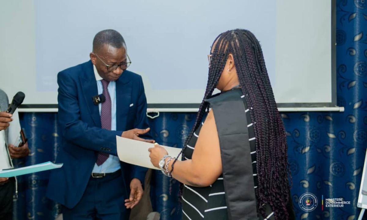 Jules Mwilu Mbo remet un brève à une femme congolaise formée par le ministère de Commerce extérieur pour promouvoir les exportations de la RDC à la ZLECAF