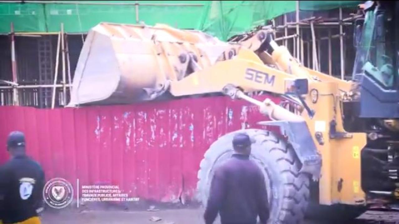 Un engin de l'hôtel de ville en pleine démolition de la palissade de la cité chinoise sur le Boulevard Sendwe