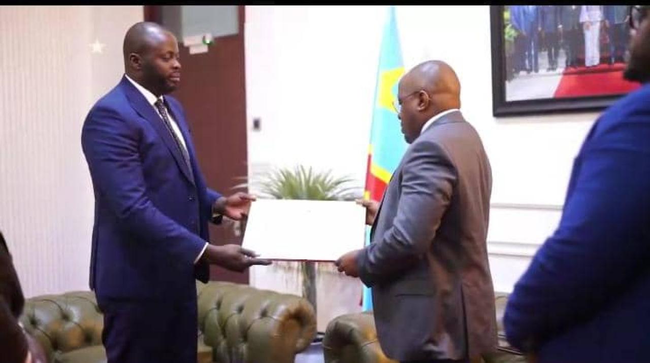 Le VPM en charge de l'Intérieur Jacquemain Shabani Lukoo recevant des mains des étudiants et chercheurs congolais établis en Belgique, un diplôme d'excellence