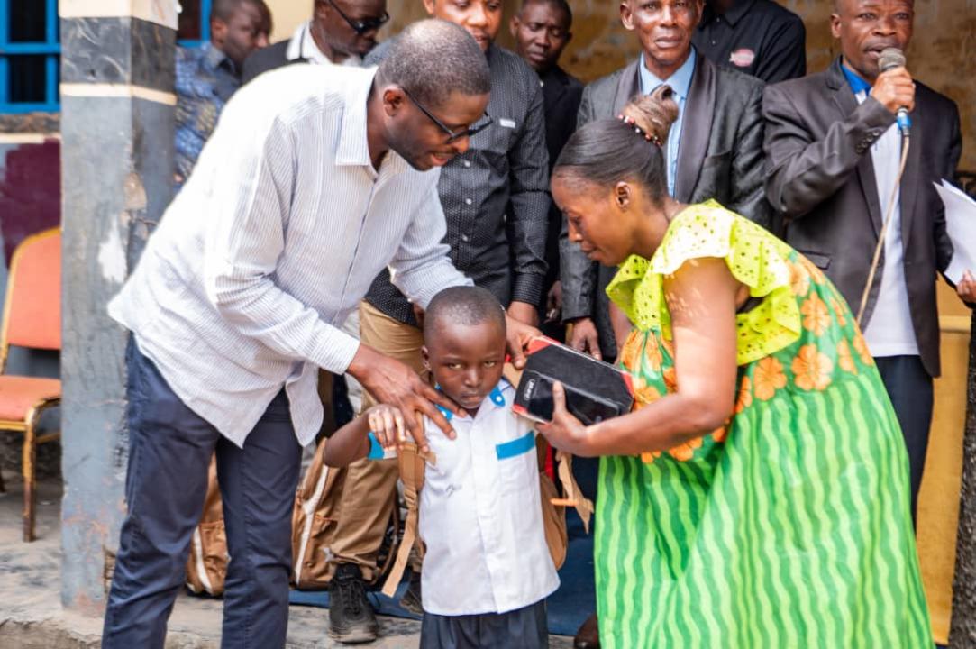 Le député national Éric Tshikuma remet à un élève l’une des 48 bourses « Patrick Muyaya », comprenant un kit scolaire ainsi que la prise en charge des frais de scolarité pour l’année scolaire 2026-2027.