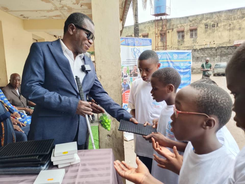 Le directeur général de l'Institut national pour aveugle,(INAV), remet une tablette adaptée à un élève malvoyant de cet établissement scolaire